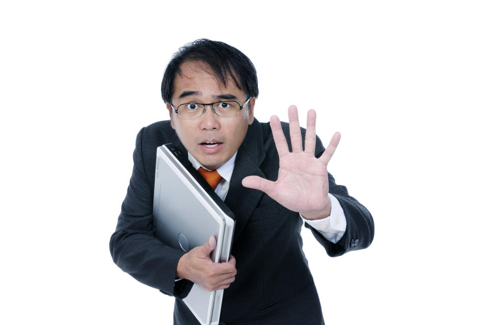 An under duress businessman holding a laptop over white background.