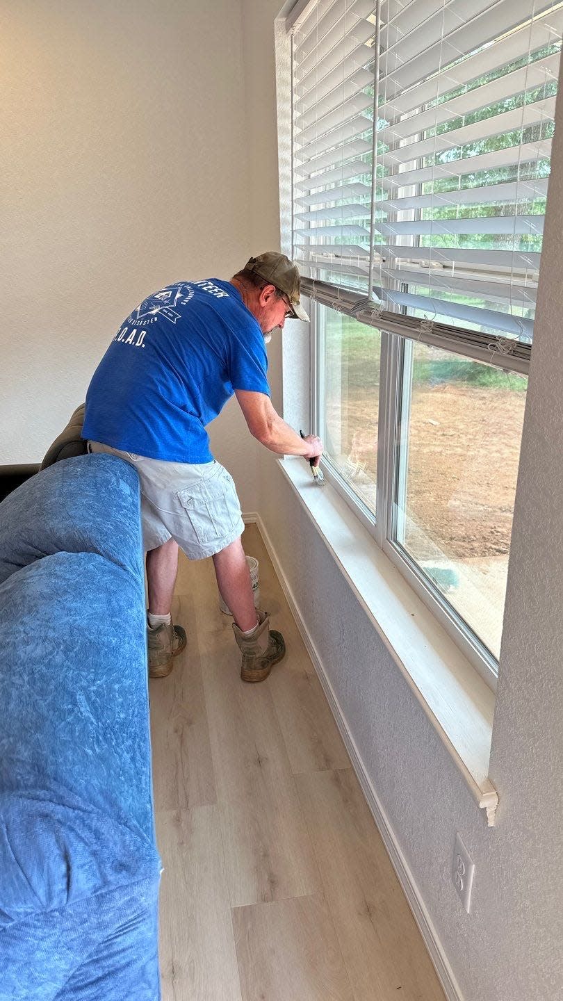 A volunteer paints a windowsill during a new home build project led by Recovering Oklahomans After Disaster and several partnering organizations.