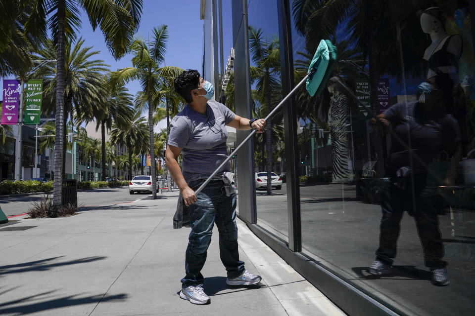 Dulce Gonzalez cleans the front window of Dolce & Gabbana on Rodeo Drive Tuesday, May 19, 2020, in Beverly Hills, Calif. (AP Photo/Ashley Landis)