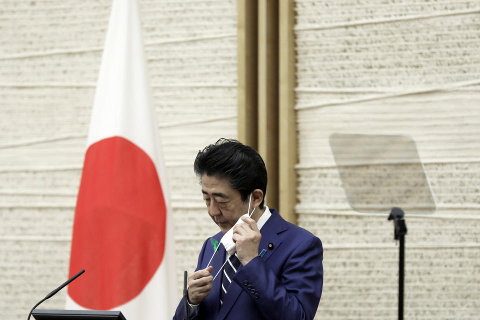 Japanese Prime Minister Shinzo Abe removes a face mask during a news conference at the prime minister's official residence in Tokyo, Friday, April 17, 2020. Abe expanded Thursday the state of emergency to step up measures ahead of a major holiday week coming up in early May so that people won’t travel around and possibly spread the virus. The ongoing state of emergency runs through May 6. (Kiyoshi Ota/Pool Photo via AP)