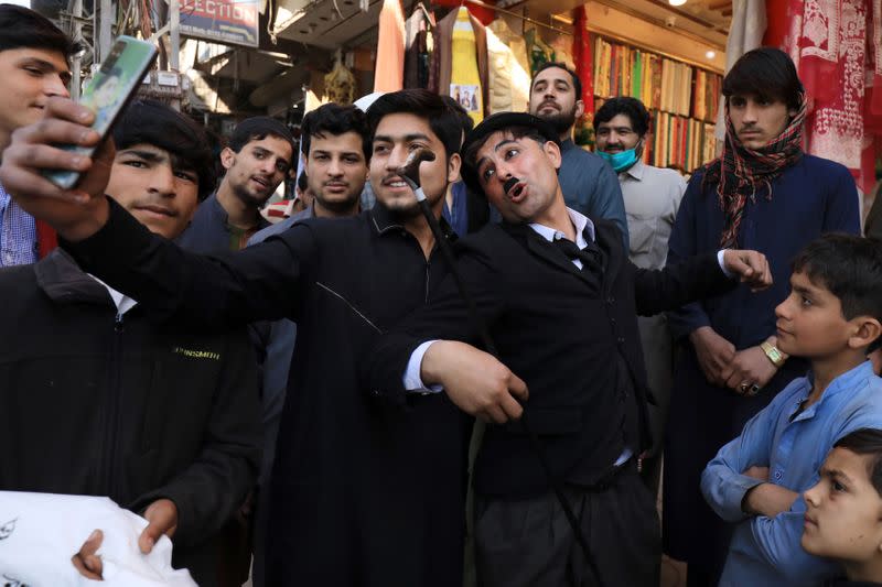 Usman Khan, 29, dressed up as Charlie Chaplin, poses for a photo with fans as he performs along the street in Peshawar