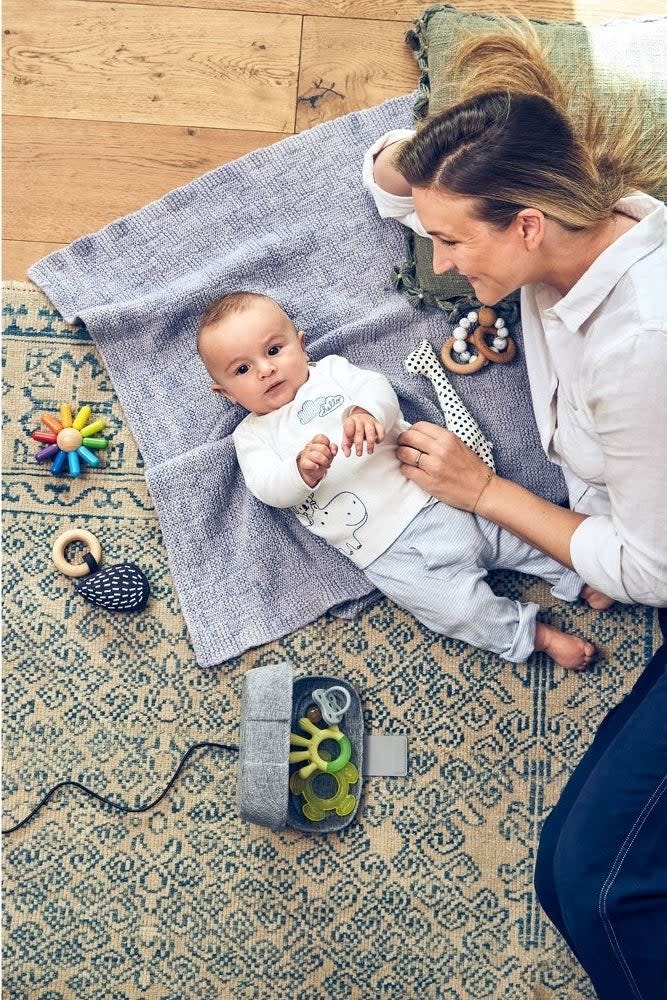 Woman sits with baby surrounded by toys, indicative of family-friendly products for an article on shopping