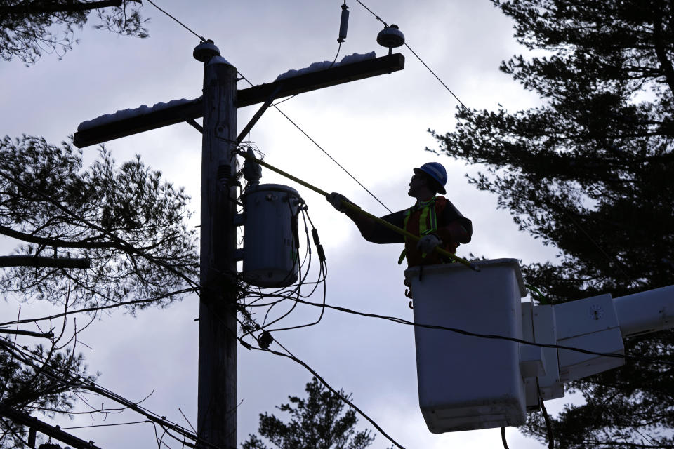 Lineman Tyler Hunter, of Newmarket, Ontario, Canada, clears pine tree limbs from electric lines in a neighborhood of about 70 houses without power, Wednesday, March 15, 2023, in Windham, N.H. After receiving nearly two feet of heavy, wet snow in Southern New Hampshire on Tuesday, workers and residents are recovering from a daylong nor'easter. (AP Photo/Charles Krupa)