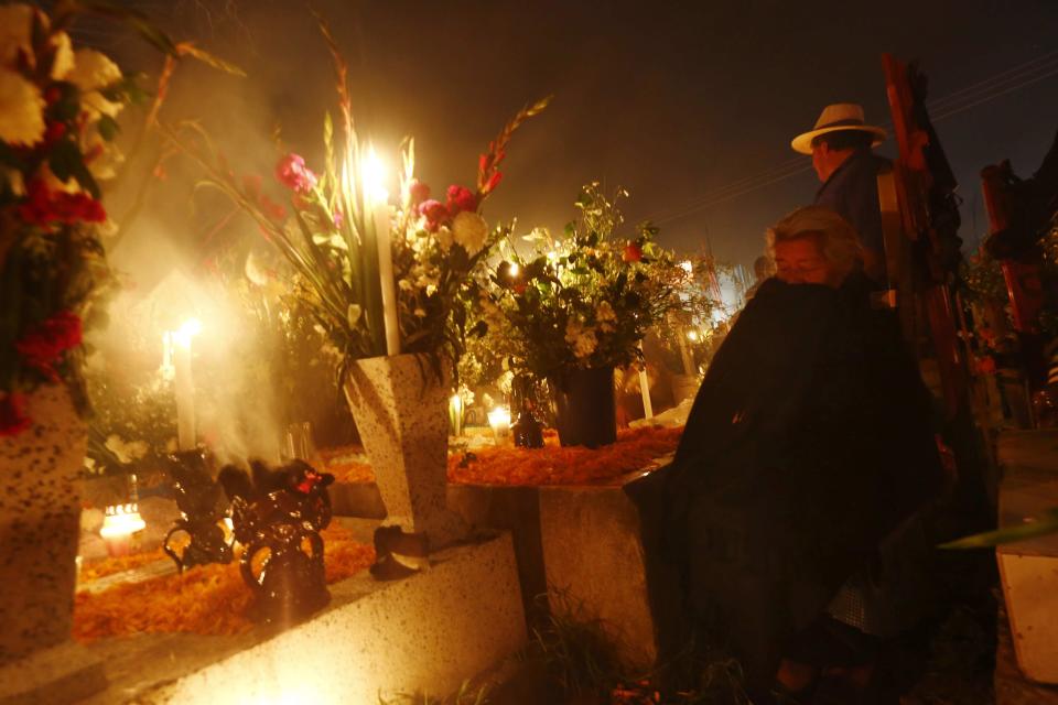 A woman pays her respects at the graves of her relatives in San Andres cemetery, Mixquic. (Reuters)