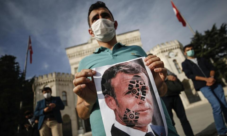 A young person holds a photograph of Emmanuel Macron stamped with a footprint