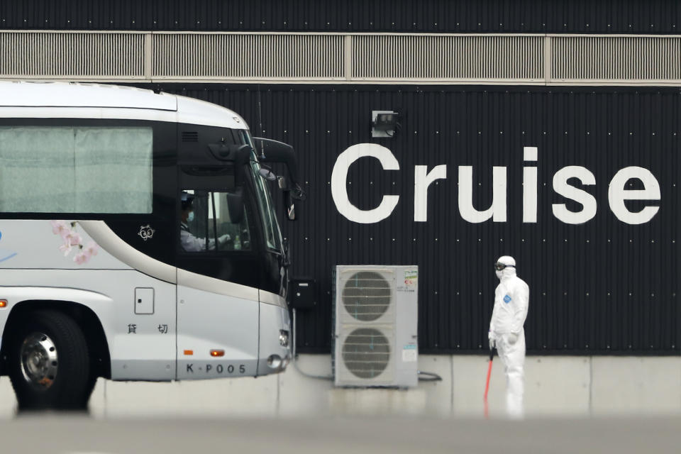 A bus carrying the passengers from the quarantined Diamond Princess cruise ship prepares to leave a port in Yokohama, near Tokyo, Thursday, Feb. 20, 2020. The cruise ship started letting passengers who tested negative for the virus leave the ship Wednesday. Test results are still pending for some people on board. (AP Photo/Eugene Hoshiko)