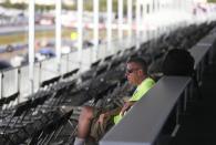 Jon Jenney, sits alone with no fans in the stand while working in the VIP area overlooking pit lane, at the IndyCar Grand Prix of St. Petersburg, Friday, March 13, 2020 in St. Petersburg. NASCAR and IndyCar have postponed their weekend schedules at Atlanta Motor Speedway and St. Petersburg, due to concerns over the COVID-19 pandemic. (Dirk Shadd/Tampa Bay Times via AP)