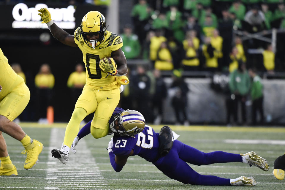 Oregon running back Bucky Irving (0) eludes a tackle by Washington cornerback Mishael Powell (23) during the first half of an NCAA college football game Saturday, Nov. 12, 2022, in Eugene, Ore. (AP Photo/Andy Nelson)