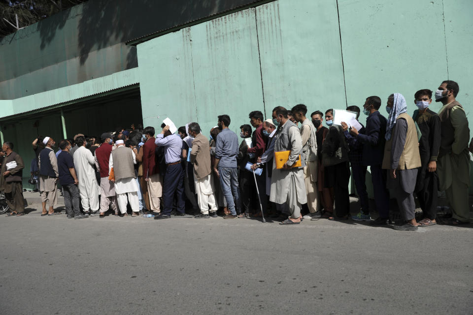 Afghans wait in long lines for hours to get visas in front of the Iranian embassy, in Kabul, Afghanistan, Sunday, Aug. 15, 2021. Officials say Taliban fighters have entered Kabul and are seeking the unconditional surrender of the central government. (AP Photo/Rahmat Gul)
