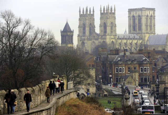 Visitors to York walk along the old City walls towards York Minster (PA)