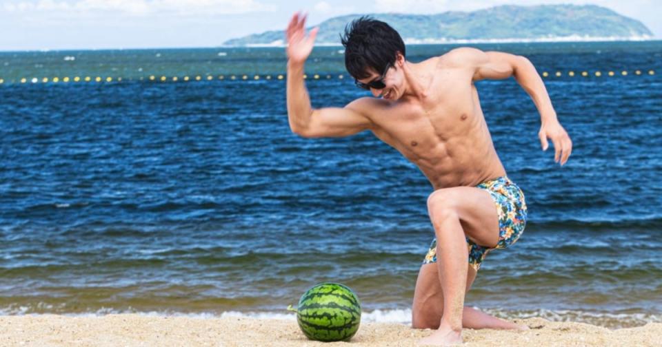 A man chops a watermelon on the beach. (Photo courtesy of freephotomuscle.com)