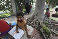 Children attend a sidewalk class for underprivileged children taught by an Indian couple, Veena Gupta and her husband Virendra Gupta, in New Delhi, India, on Sept. 3, 2020. It all began when Veena's maid complained that with schools shut, children in her impoverished community were running amok and wasting time. The street-side classes have grown as dozens of children showed keen interest. Now the Guptas, with help from their driver, teach three different groups three times a week, morning and evening. As most schools in India remain shut since late March when the country imposed a nationwide lockdown to curb the spread of COVID-19, many switched to digital learning and taking classes online. (AP Photo/Manish Swarup)