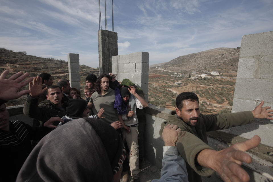 Palestinians (front and L) try to prevent fellow Palestinians from the village of Qusra from beating up a group of Israeli settlers as they are cornered at a construction site after they sparked clashes upon entering the village near Nablus, on January 7, 2014. (JAAFAR ASHTIYEH/AFP/Getty Images)