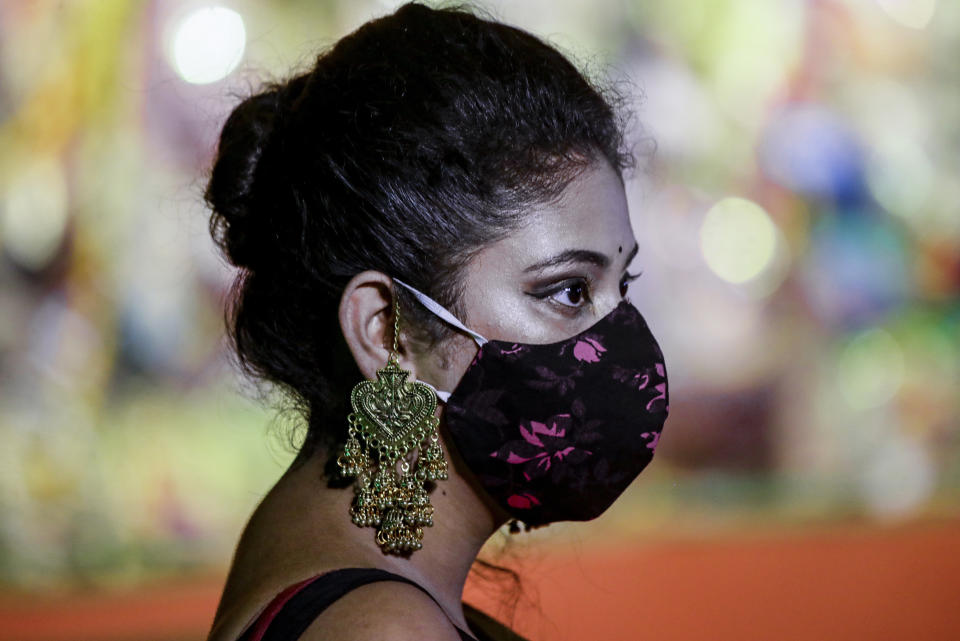 A Hindu devotee wearing face mask and ornaments visits an almost deserted worship venue of Hindu goddess Durga during Durga Puja, the biggest festival of the region, in Kolkata, India, Sunday, Oct. 25, 2020. The Hindu festival season is traditionally laced with an unmatched fanfare and extravaganza, with socializing being the hallmark of the celebration. But because of the coronavirus pandemic this year's festivities have started on a pale note. (AP Photo/Bikas Das)