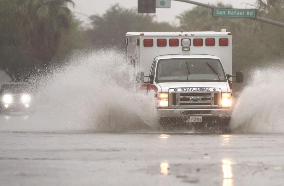 An ambulance drives through a flooded street in Palm Springs as Tropical Storm Hilary approaches.