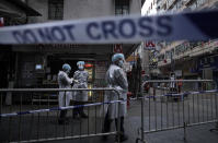 Government workers wearing personal protective equipment stand guard at the closed area in Jordan district, in Hong Kong, Sunday, Jan. 24, 2021. Thousands of Hong Kong residents were locked down Saturday in an unprecedented move to contain a worsening outbreak in the city, authorities said. (AP Photo/Vincent Yu)