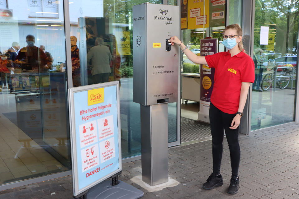 HAMBURG, GERMANY - MAY 28: A employee of Netto market presents the first protective face mask vendor for supermarket chain Netto during the Coronavirus crisis on May 28, 2020 in Steilshoop, Hamburg, Germany. The self-service vendor called "Maskomat" by Flavura is placed in front of the grocery store to provide customers with single-use protective face masks for one Euro each. (Photo by Tristar Media/Getty Images)