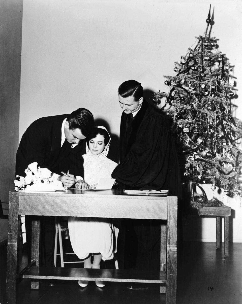 <p>Natalie Wood and Robert Wagner sign their wedding license with the priest after saying "I do" the week between Christmas and New Years in 1957. The couple sadly divorced in 1962, but remarried again in 1972. </p>