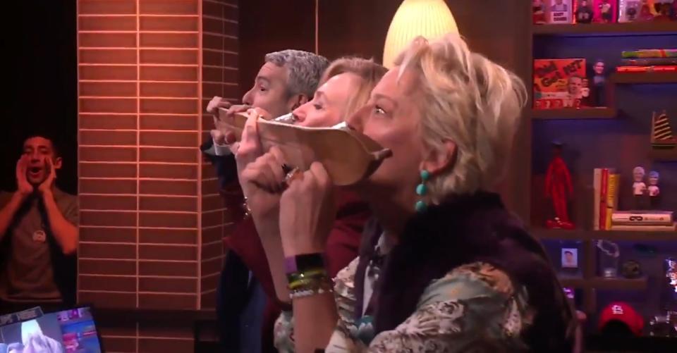 Andy Cohen, Hillary Clinton, and Dorinda Medley drinking out of a shotski