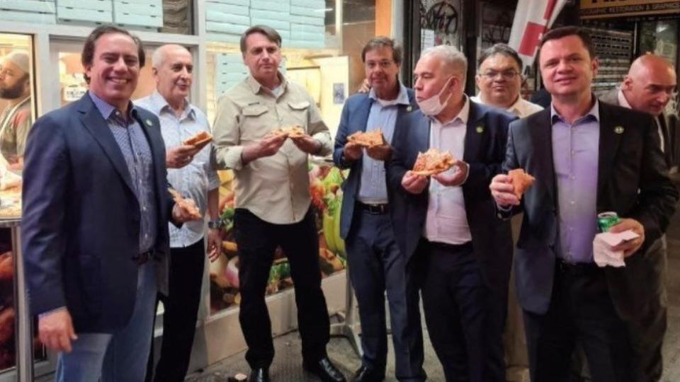 El presidente de Brasil, Jair Bolsonaro (tercero de izq. a der.) come pizza acompañado del presidente del Banco Federal Pedro Guimaraes, el general Luiz Eduardo Ramos, el ministro de Turismo Gilson Machado Neto y el ministro de Salud Marcelo Queiroga.