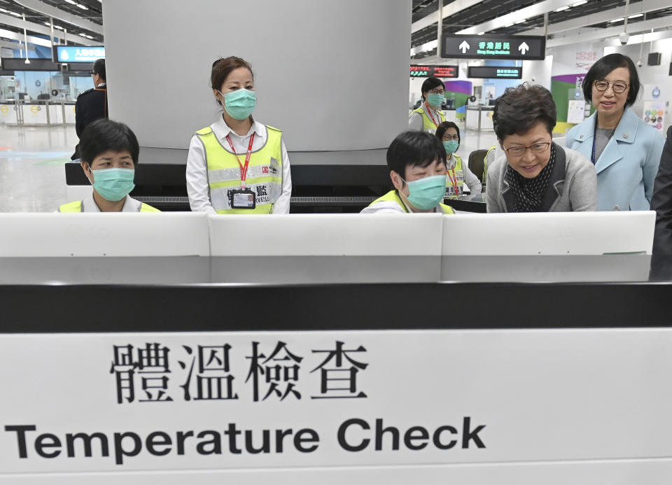 In this Friday, Jan. 3, 2020, photo released by Hong Kong Government Information Service, Hong Kong Chief Executive Carrie Lam, second from right, accompanied by Secretary for Food and Health, Prof. Sophia Chan, right, reviews the health surveillance measures by officers of the Port Health Division at West Kowloon Station in Hong Kong. Hong Kong authorities activated a newly created “serious response" level Saturday, Jan. 4, 2020, as fears spread about a mysterious infectious disease that may have been brought back by visitors to a mainland Chinese city. Lam urged any travelers who develop respiratory symptoms to wear surgical masks, seek medical attention and let doctors know where they have been. (Hong Kong Government Information Service via AP)