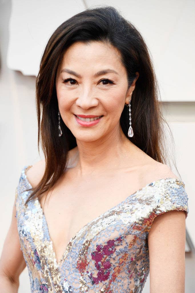 A close-up of Michelle smiling at a red carpet event while wearing a off-the-shoulder sequined dress