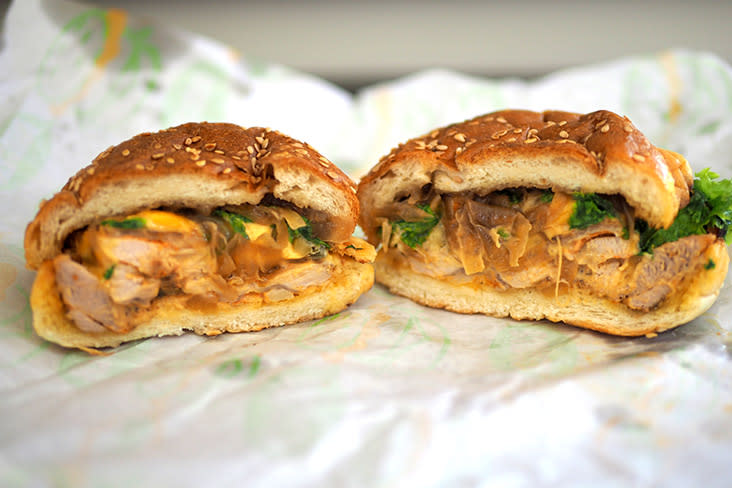 A cross section of the Cajun grilled chicken burger that has caramelised onions and vegetables with a soft brioche bun