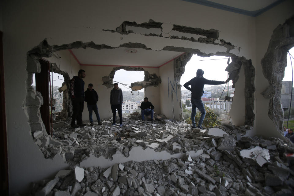 Palestinians examine a house after it was partially demolished by the Israeli army in the village of Shweikeh, near the West Bank city of Tulkarem, Monday, Dec. 17, 2018. The Israeli military has partially demolished the home of Ashraf Naalweh, a Palestinian accused of killing two Israelis in a West Bank attack two months ago. (AP Photo/Majdi Mohammed)