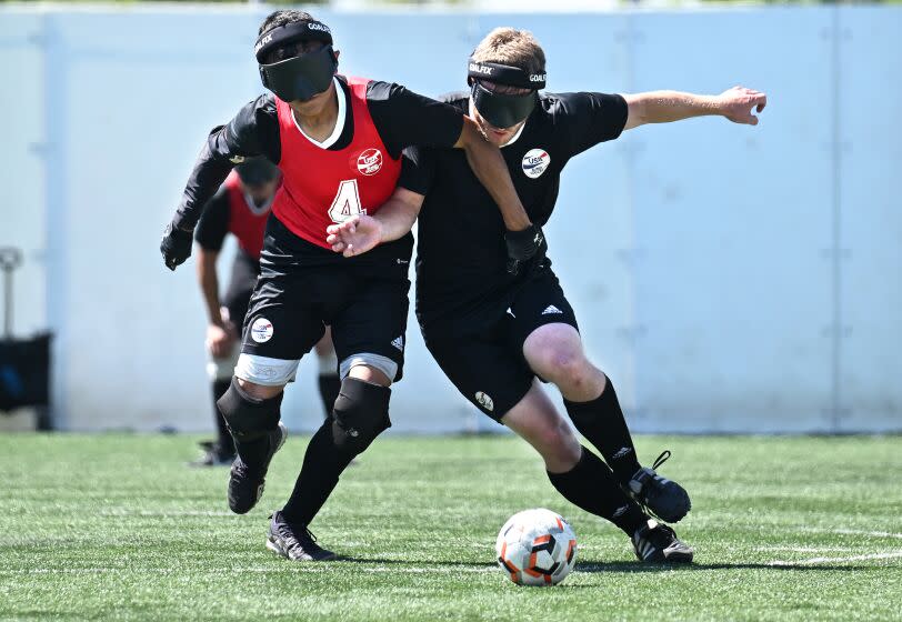 Blind soccer players Ricardo Castaneda and Noah Beckman wear goggles and battle for the ball