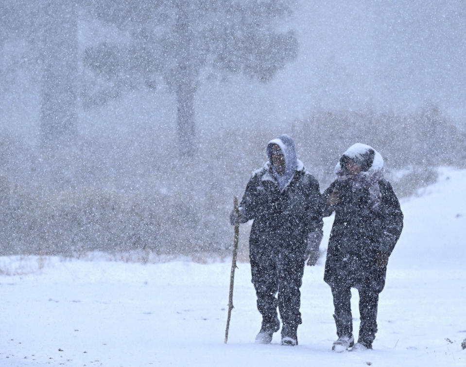 Wrightwood residents Nick and Christine Hoban enjoy a walk together as heavy snow falls on Highway 2 near Wrightwood, Calif., on Monday, Dec. 12, 2022. (Will Lester/The Orange County Register via AP)