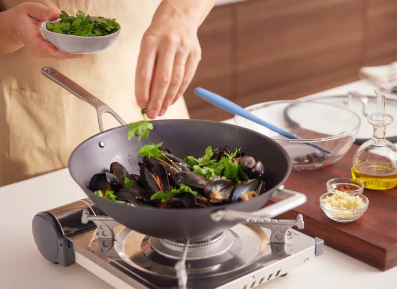 Someone using Misen cookware to make steamed mussels.