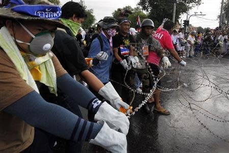 Anti-government protesters remove razor wire at the police barricade near the Government house in Bangkok November 25, 2013. REUTERS/Kerek Wongsa