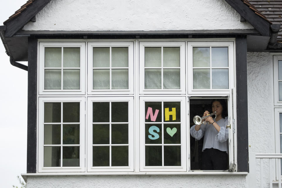 National Youth Orchestra of Great Britain trumpet player Tian Hsu, 16, takes part in a socially distanced orchestra performance of Beethoven's "Ode to Joy" from a window of her home in south west London, during the lockdown to try and stop the spread of coronavirus, Friday, April 17, 2020. The members of the National Youth Orchestra, took part in the coordinated Ode to Joy-a-thon on Friday, each giving their own 40 second performance, with photos or videos taken by their families to share on social media. They dedicated the performance to the National Health Service staff, key workers, and people who feel isolated in their homes during the lockdown. (AP Photo/Matt Dunham)