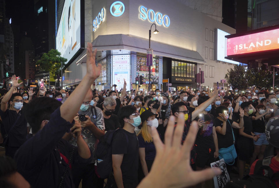 Protesters singing and gesture with five fingers, signifying the "Five demands - not one less" during a protest in Causeway Bay, Hong Kong, Friday, June 12, 2020. Protesters in Hong Kong got its government to withdraw extradition legislation last year, but now they're getting a more dreaded national security law, and the message from Beijing is that protest is futile. (AP Photo/Vincent Yu)