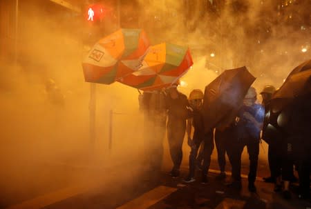 Pro-democracy protesters shield themselves with umbrellas in tear gas as they clash with police in Hong Kong
