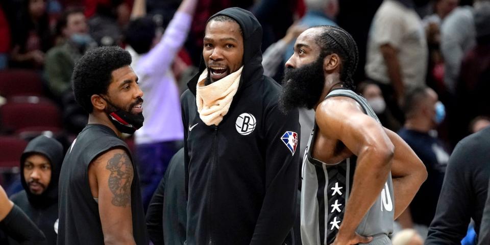 Kyrie Irving, Keevin Durant, and James Harden stand on the court talking during a game in January 2022.