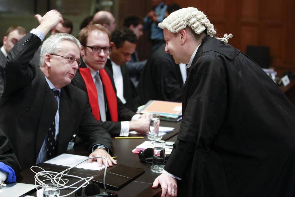 Counsel Philippe Sands of Croatia, right, speaks with Andreas Zimmermann of the Serbian delegation, left, prior to the start of public hearings at the International Court of Justice (ICJ) in The Hague, Netherlands, Monday, March 3, 2014. Croatia is accusing Serbia of genocide during fighting in the early 1990's as the former Yugoslavia shattered in spasms of ethnic violence, in a case at the United Nations' highest court that highlights lingering animosity in the region. Croatia is asking the ICJ to declare that Serbia breached the 1948 Genocide Convention when forces from the former Federal Republic of Yugoslavia attempted to drive Croats out of large swaths of the country after Zagreb declared independence in 1991. (AP Photo/Jiri Buller)