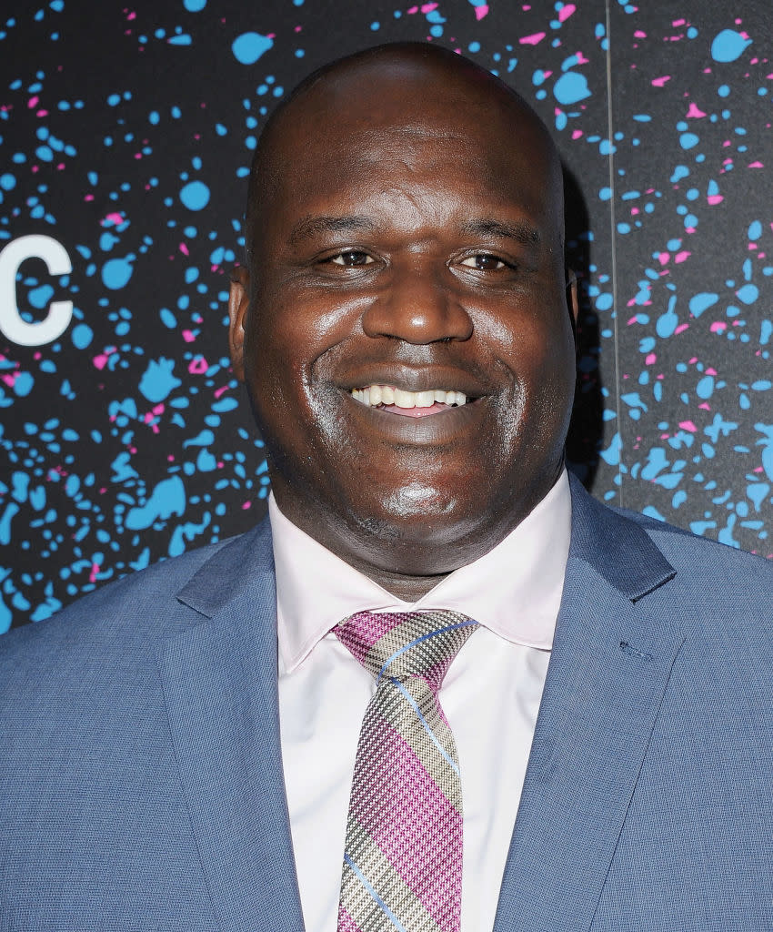 Shaquille O'Neal wearing a suit with a tie, smiling at an event