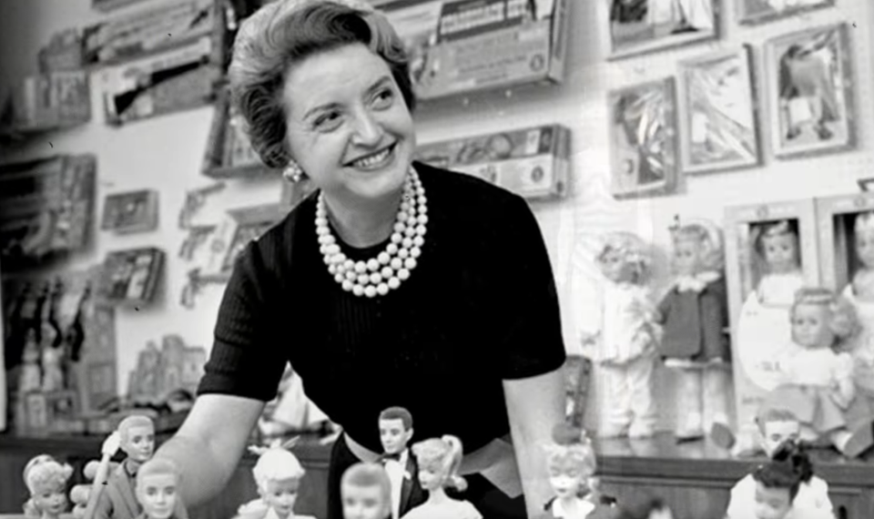 Ruth Handler leaning over a table of dolls