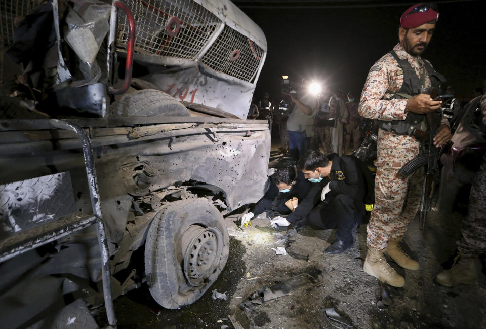 Pakistani security officials examine the site of explosion, in Karachi, Pakistan, Monday, March 15, 2021. The roadside bomb went off near a vehicle carrying paramilitary rangers in southern Pakistan on Monday, killing and wounding some people, mostly pedestrians, authorities said. (AP Photo/Fareed Khan)