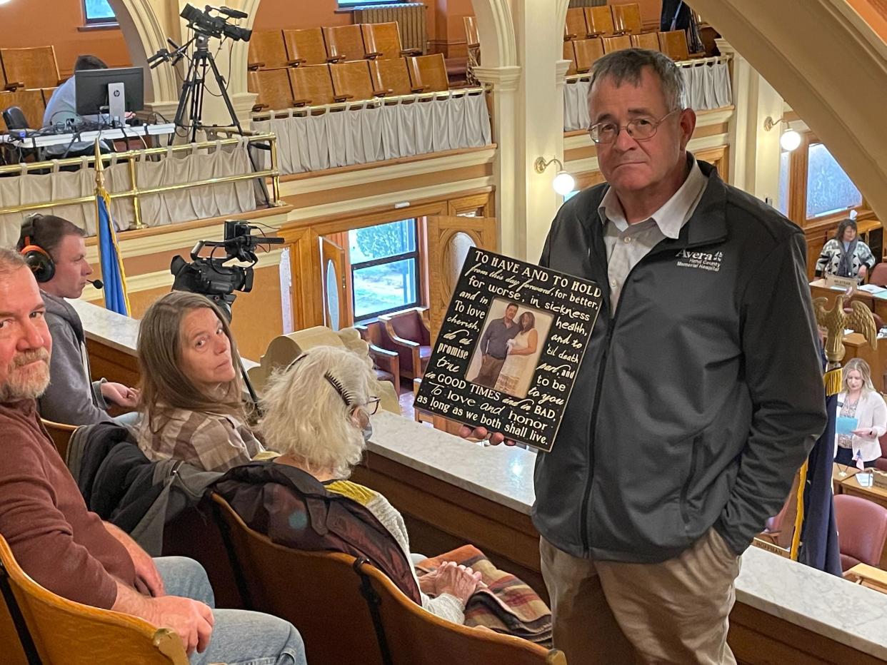 Nick Nemec, the cousin of Joseph Boever, poses with a wedding photo of Boever in the South Dakota House gallery before lawmakers voted to impeach Attorney General Jason Ravnsborg.