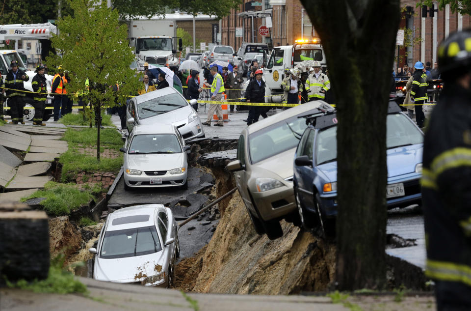 Cars sit on the edge of a sinkhole in the Charles Village neighborhood of Baltimore, Wednesday, April 30, 2014, as heavy rain moves through the region. Road closures have been reported due to flooding, downed trees and electrical lines elsewhere in the Mid-Atlantic. The National Weather Service issued flash flood warnings through Wednesday afternoon in Washington, northern Virginia and central Maryland. (AP Photo)