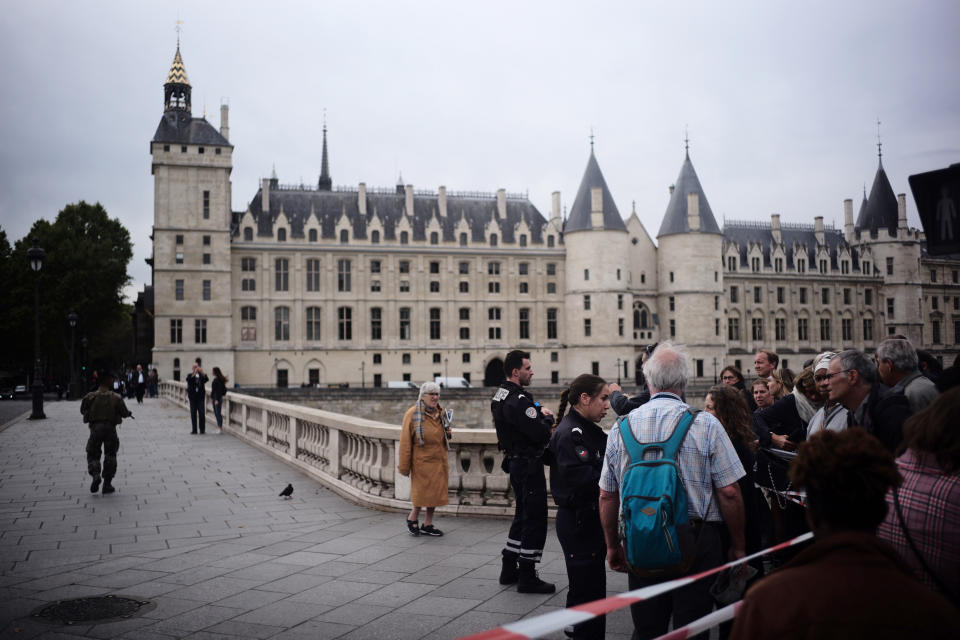 People stand behind a police tape as they are evacuated nearby the police headquarters after an incident in Paris, Thursday, Oct. 3, 2019. A French police union official says an attacker armed with a knife has killed one officer inside Paris police headquarters before he was shot and killed. (AP Photo/Kamil Zihnioglu)