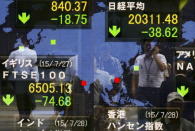 People are reflected in a board showing market indices in Tokyo July 28, 2015. REUTERS/Thomas Peter