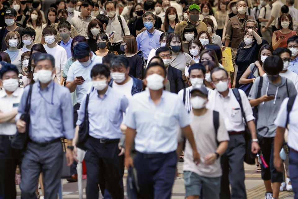 People wearing face masks to help curb the spread of the new coronavirus walk across a street in Osaka, Japan, Wednesday, July 29, 2020. As Japan battles a surge in coronavirus cases, some areas may be running out of isolation facilities to monitor infected people.(Kyodo News via AP)