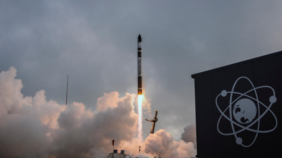  A black and white rocket launches into a cloudy sky. 