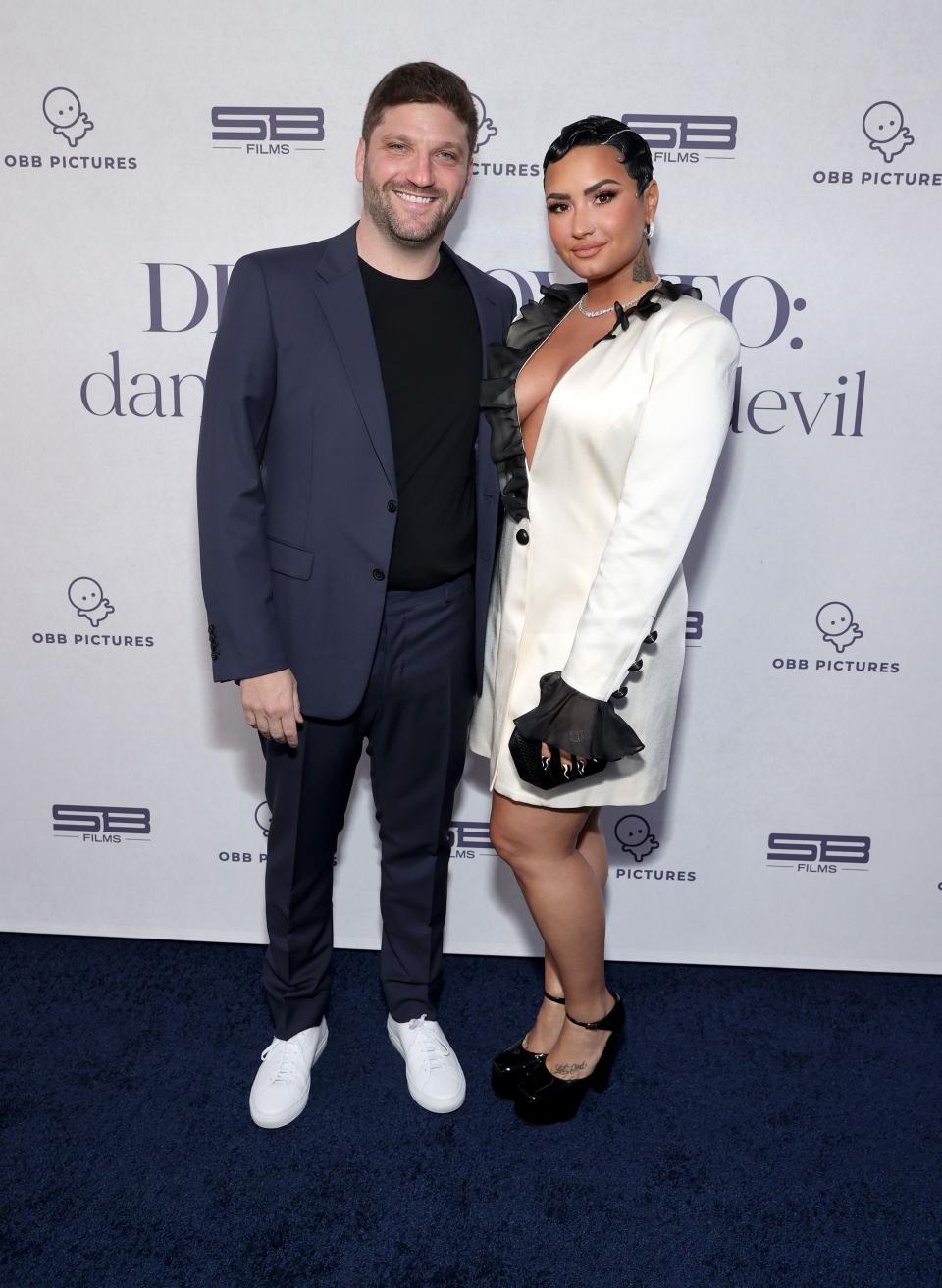 Michael D. Ratner and Demi Lovato are posing together on a red carpet