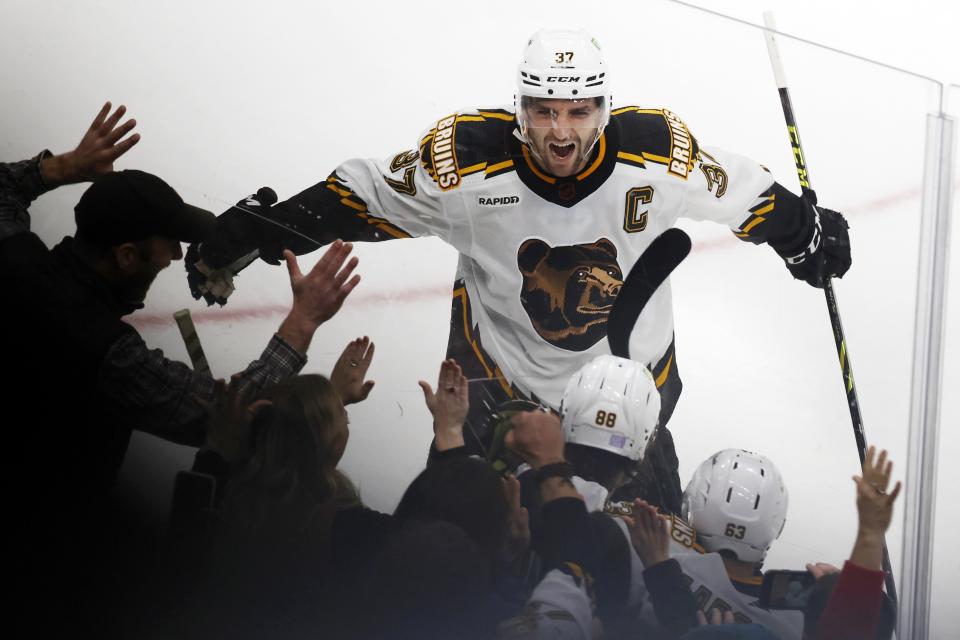 Boston Bruins' Patrice Bergeron (37) celebrates the goal by David Pastrnak (88) in overtime during an NHL hockey game against the Carolina Hurricanes, Friday, Nov. 25, 2022, in Boston. (AP Photo/Michael Dwyer)