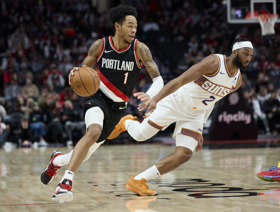 Portland Trail Blazers guard Anfernee Simons, left, dribbles past Phoenix Suns forward Josh Okogie, right, during the second half of an NBA basketball game in Portland, Ore., Sunday, Jan. 14, 2024. (AP Photo/Craig Mitchelldyer)