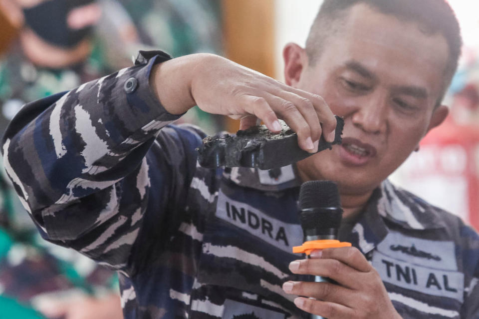 A Indonesian Navy personnel shows a piece of debris believed to be from the sunken submarine.